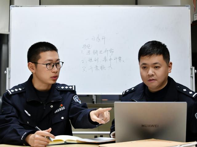 龚晨（左）与办案民警一道进行资金分析（上海市公安局 供图）