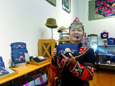     ▲ 张丽琼向“芬芳观察团”介绍公司生产的彝绣包袋。