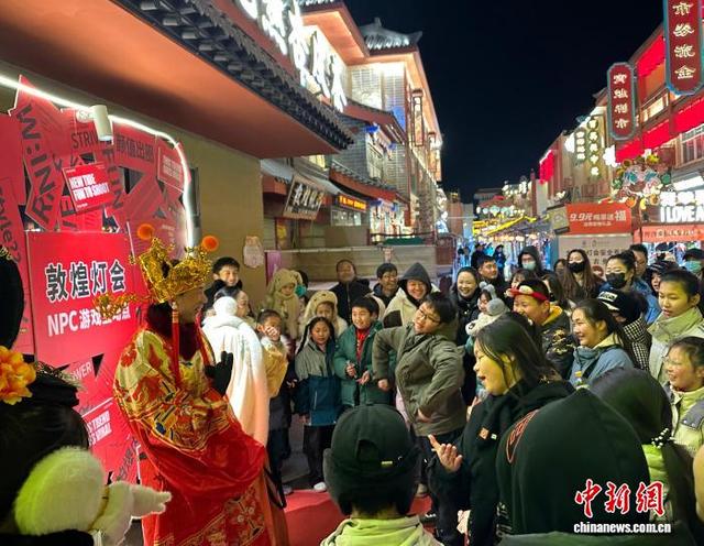 2026年1月9日晚，甘肃敦煌，游客与“财神”游戏互动。中新社记者 丁思 摄